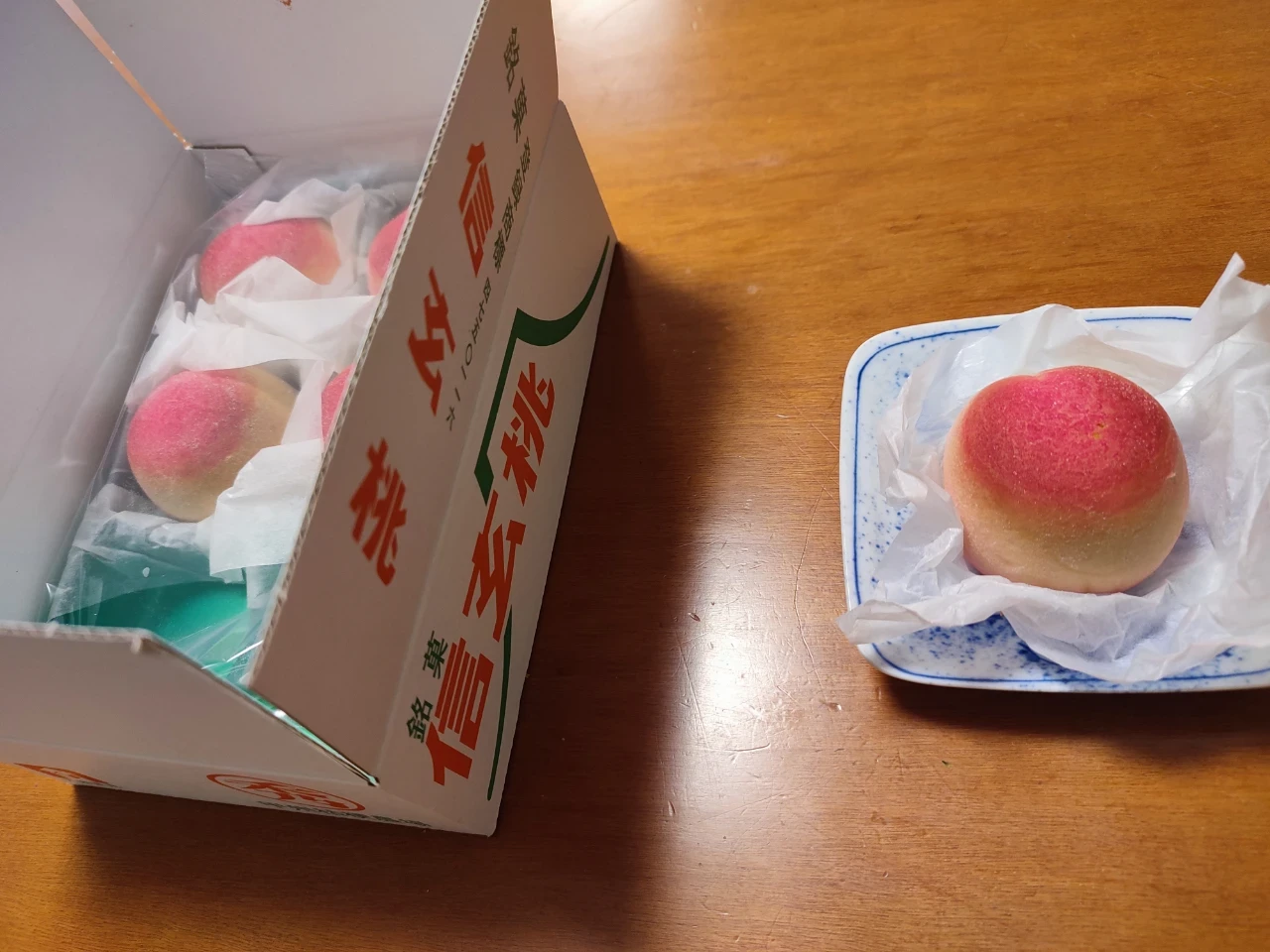 信玄桃という和菓子の写真。外見が桃に似ていて、果物用のダンボール箱を模したパッケージに入っている。