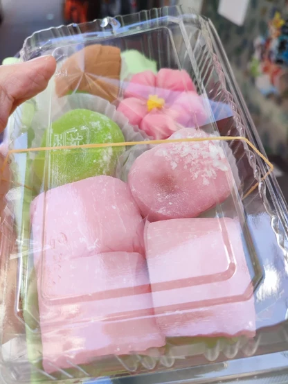 和菓子が7つ入ったプラケースの写真。手前に桃色のすあまが見える。