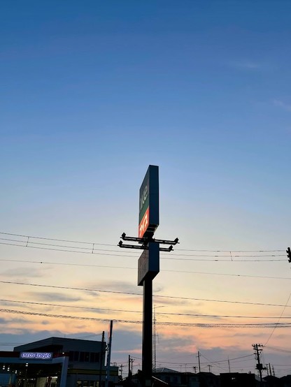 青から薄オレンジのグラデーションの空　真ん中にナイスの看板ポール