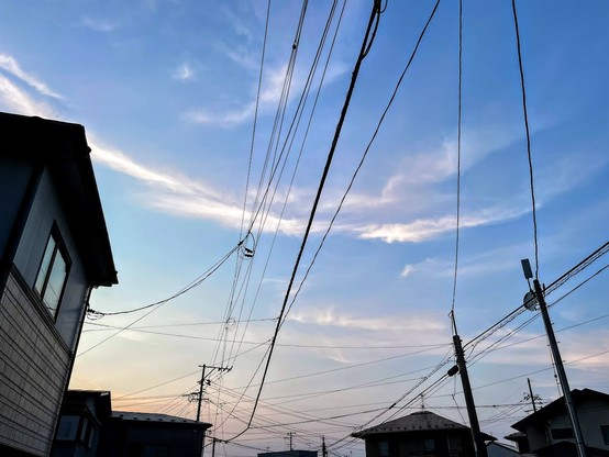 青から薄オレンジのグラデーションの空　円弧状の雲が数本